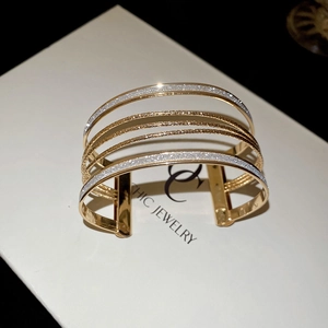 Detail of layered gold open cuff bracelet with sparkling glitter and smooth metal bands