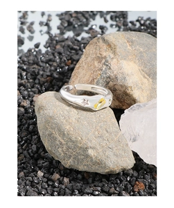 Macro shot of silver S925 ring with yellow gemstone and star engraving on grey stone