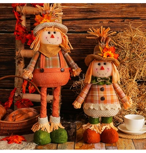 Detail of harvest scarecrow dolls with maple leaves and straw hats in autumn scene