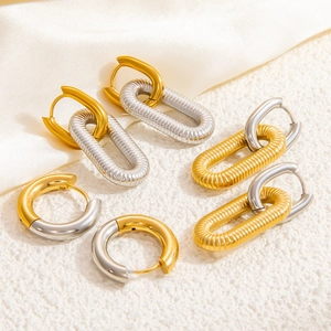 Three pairs of stylish gold and silver two-tone stainless steel hoop earrings on silk