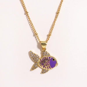 Macro shot of gold fish pendant with purple enamel and sparkling crystals on chain