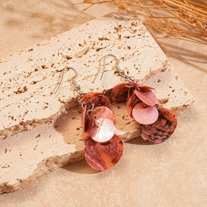 Vue détaillée de boucles d'oreilles géométriques en nacre rose sur une pierre