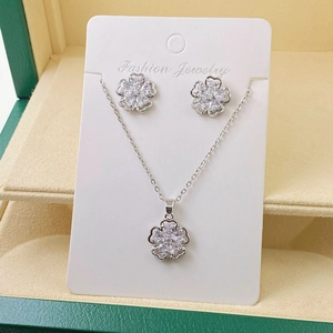 Silver clover necklace and earrings set with zircons in a green jewelry box