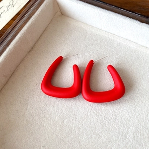 Vue détaillée de boucles d'oreilles rouges en U avec finition mate sur plateau en velours