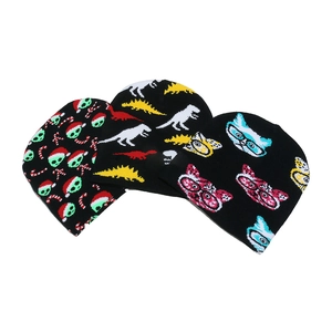 Three knit beanies featuring alien, dinosaur, and cat patterns on black wool fabric