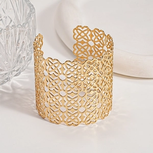 Dettaglio del bracciale rigido dorato con cuori traforati in una scenografia elegante