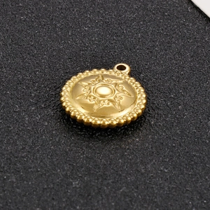Detailed close-up of golden sun pendant with bead edge on black textured surface