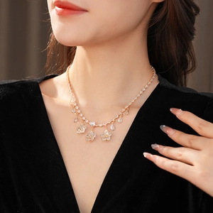 Close-up of gold flower necklace with zircon teardrop pendant on female model