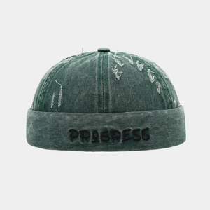 Dettaglio del cappello docker verde vintage con ricamo PROGRESS e finiture in denim lavato