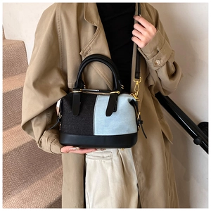 Dettaglio borsa patchwork in denim con manici in pelle nera e finiture dorate