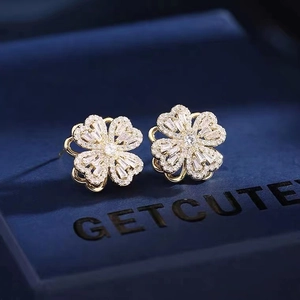 Elegant rotating golden clover earrings with white zircon on blue velvet box