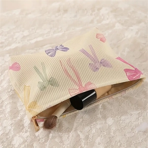 Corduroy makeup bag with colorful bow print and golden zipper for cosmetic storage