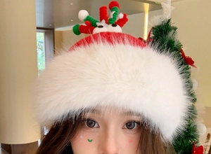 Close-up of red plush Christmas hat featuring reindeer antlers and cartoon eye details