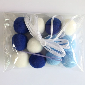 DIY colorful pompoms set with blue and white fuzzy balls, ribbon, and threading needle