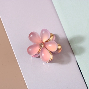 Close-up of a pink resin flower hair claw with a gold metal base and rhinestone