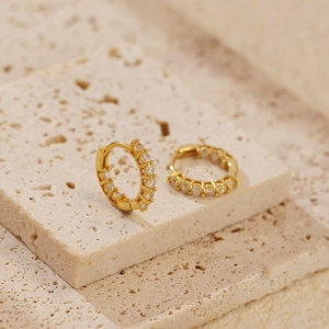 Macro shot of gold S925 sterling silver huggie hoops with sparkling cubic zirconia