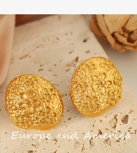 Detail of 18k gold plated square woven flower earrings on a natural stone base