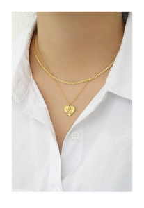 Detail shot of a double-layered golden heart angel relief necklace on a white shirt collar