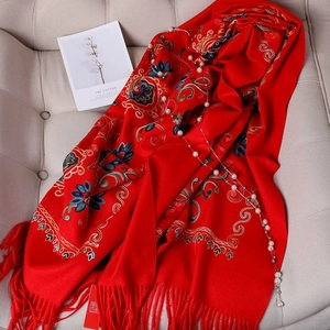 Detail of red floral embroidery on thick cashmere-feel scarf with elegant tassels