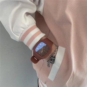 Close-up of a brown square sports watch with silicone strap and metal tag on wrist