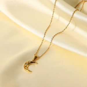 Macro view of 18K gold stainless steel moon pendant with three zircons on silk