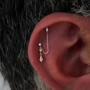 Close-up of gold double chain earrings with tassels and sparkling diamond pendants
