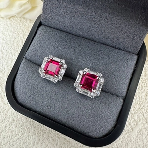 Macro shot of 6x6mm Asscher cut ruby stud earrings in a premium black velvet jewelry box