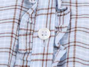 Detailed close-up of plaid fabric with buttons and ruffled trim on a short dress