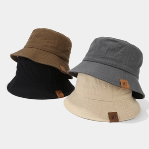 Dettaglio di quattro cappelli a secchiello in cotone con etichette in pelle marrone