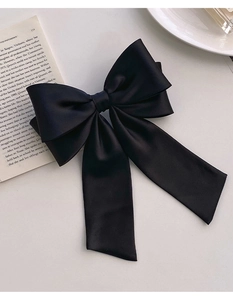 Close-up of black satin oversized bow hair clip on vintage books for an elegant French style