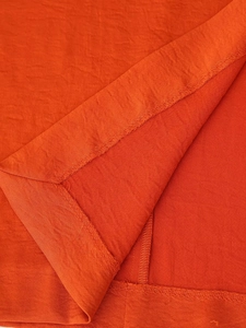 Close-up of orange satin fabric showing refined texture and high-quality stitching detail