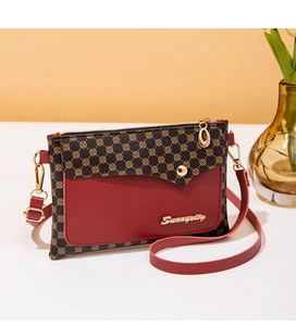 Detail of red and brown contrast leather crossbody bag with golden clover print pattern