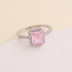 Elegant silver ring with emerald-cut pink zircon and halo stones on a neutral background