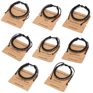 Dettaglio di otto braccialetti in pelle Morse Code su cartoncini kraft da uomo
