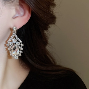 Close-up of a glamorous silver waterdrop earring with rhinestones on model's ear