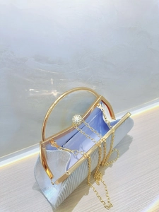 Detail of silver pleated evening clutch with gold handle and sparkling rhinestone clasp