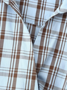Close-up of the collar detail on a brown and blue plaid poplin shirt with neat stitching