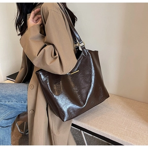 Detail of soft dark brown leather tote bag with vintage texture and gold metal bar accent