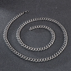 Detail of dark grey Cuban link chain with a secure lobster clasp on textured background