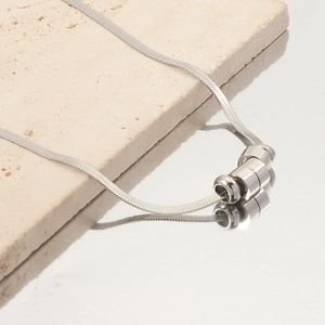 Macro shot of a silver bead pendant necklace on snake chain with reflective mirror surface