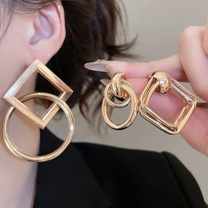 Detailed view of large gold geometric earrings with square and circular interlocking design