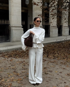 Détail d'un ensemble en tricot blanc avec haut à manches évasées et pantalon large