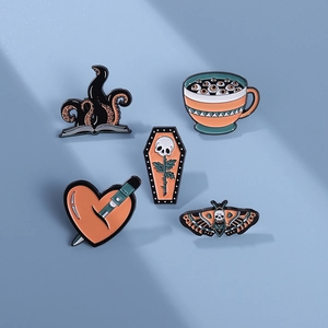 Five-piece gothic enamel pin set featuring skulls, moths, and hearts on blue background