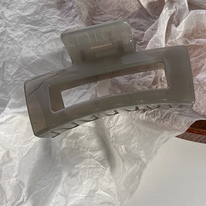 Dettaglio molletta per capelli grigio traslucido con design traforato su carta