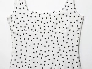 Détail de l'encolure ronde et de l'imprimé à pois noirs sur une robe en mousseline blanche