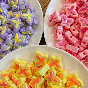 Colorful butterfly acrylic beads for DIY jewelry making in small white ceramic bowls