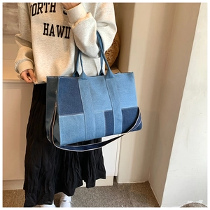 Detail of blue denim patchwork tote bag with white stitching and adjustable strap