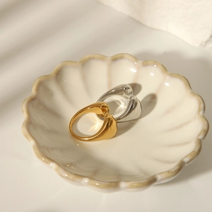 Detailed view of polished irregular open rings in gold and silver on a ceramic shell dish