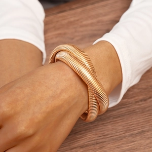 Detailed view of rose gold textured wrap bracelet on wrist with elegant knit sleeve