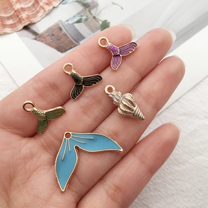 Size comparison of ocean alloy pendants with colorful fish tails and golden seashell charm